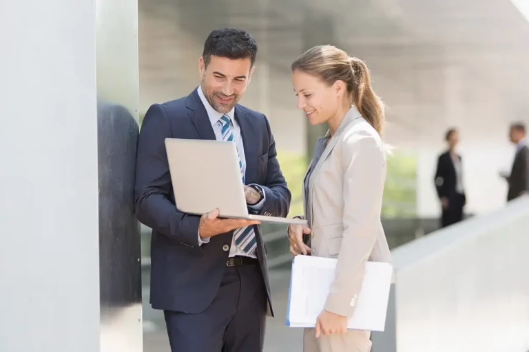 Corporate business people using laptop outdoors